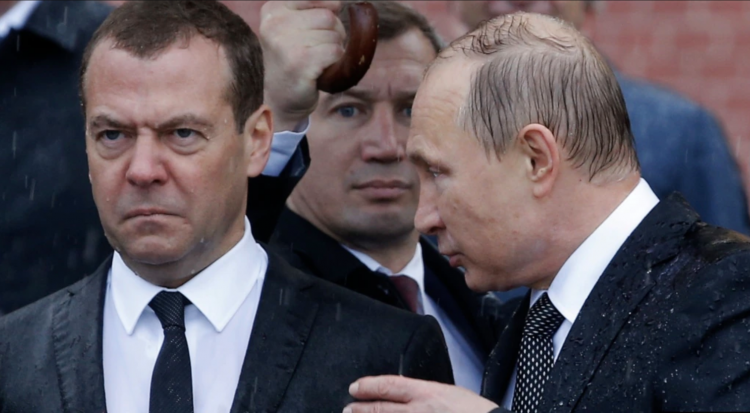 Russian President Vladimir Putin (right) speaks with Prime Minister Dmitry Medvedev in the rain during a ceremony at the Kremlin in Moscow in June 2017.
