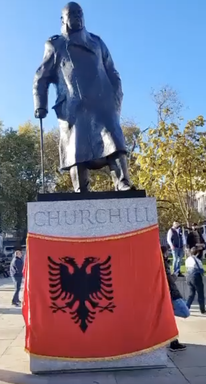 Albanian flag wrapped around Churchill during protests against Braverman, Nov 2022